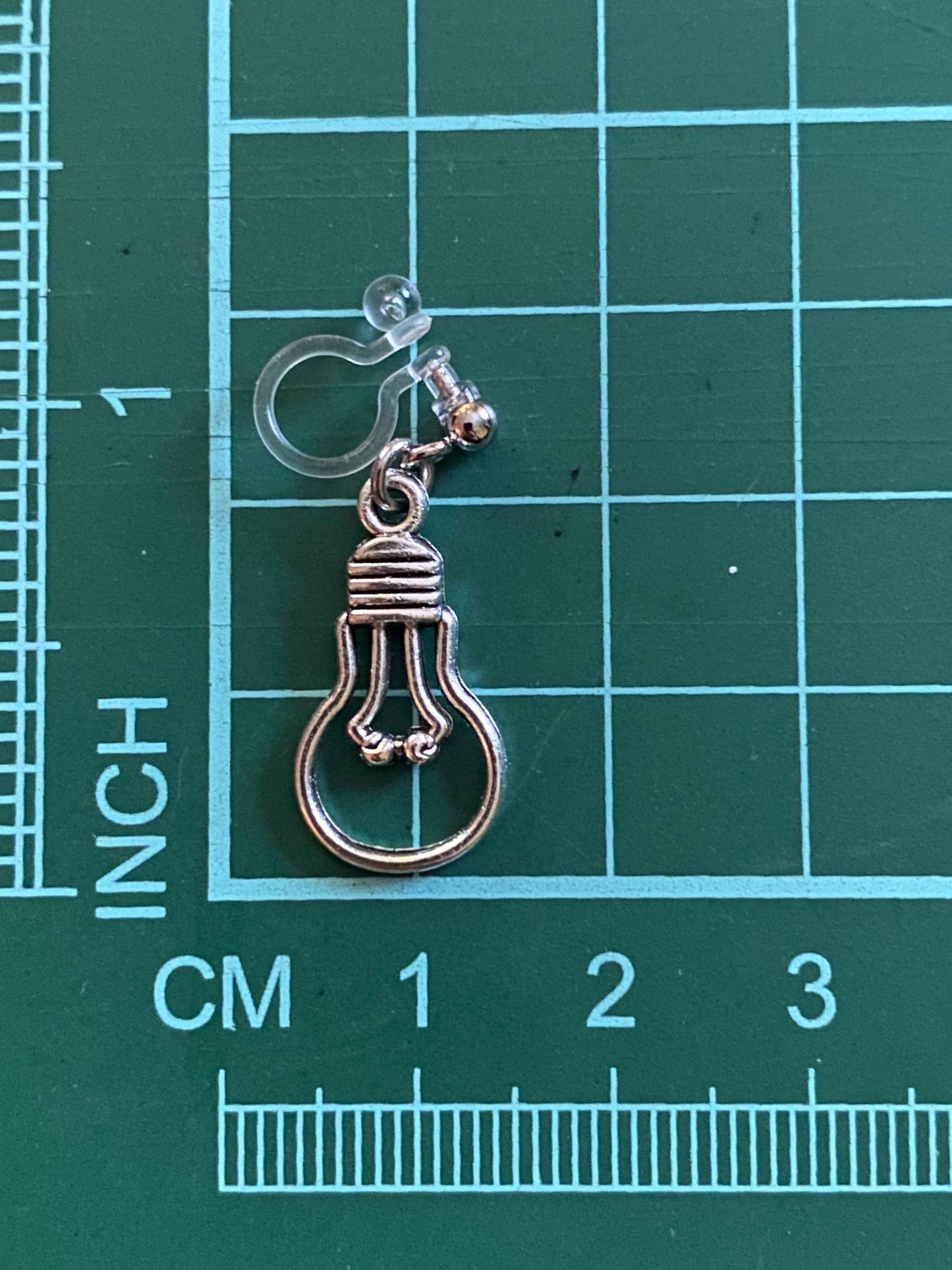 Dangling invisible clip on earrings with silver coloured lightbulb pendants