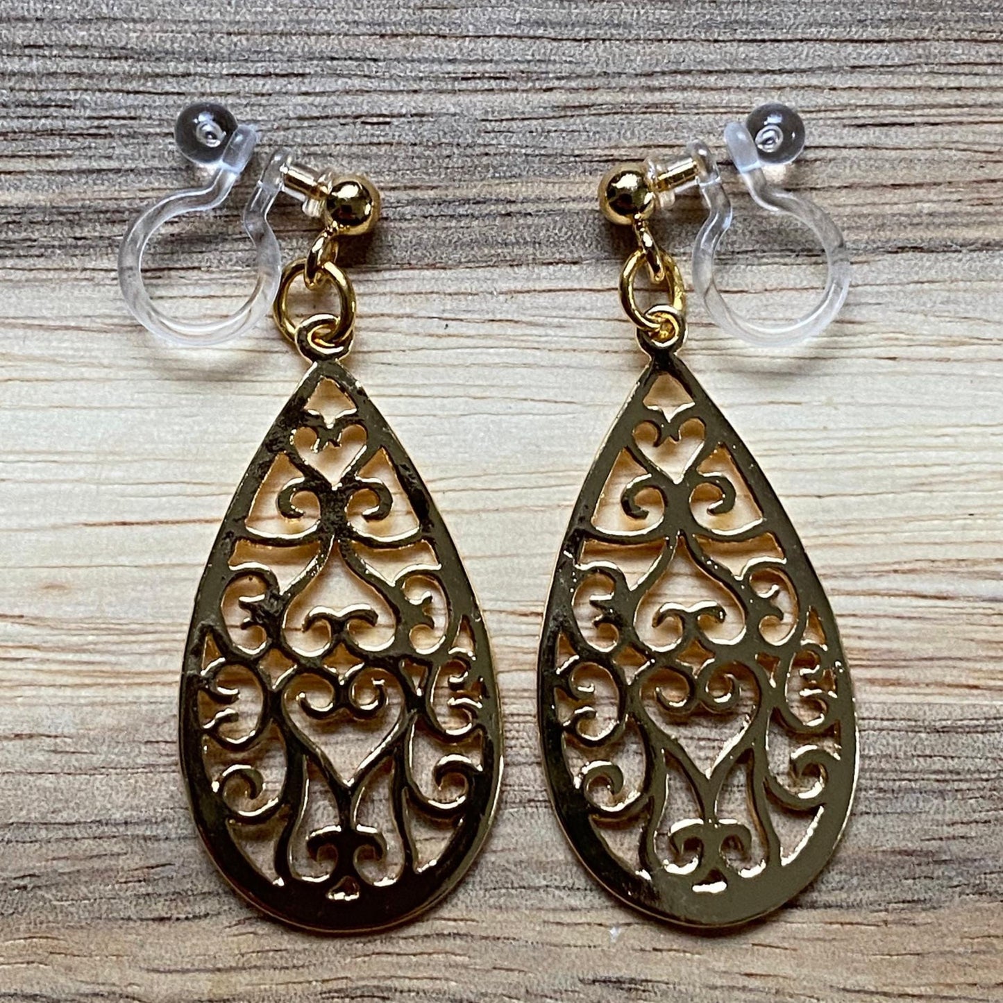 Dangling invisible clip on earrings with gold coloured teardrop pendants