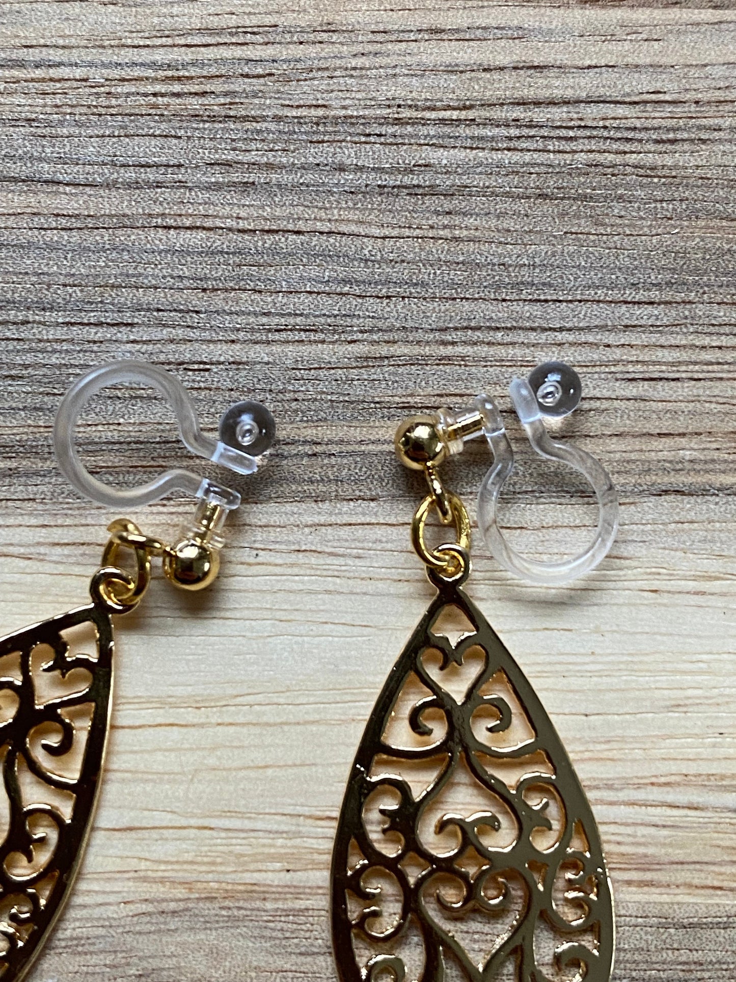 Dangling invisible clip on earrings with gold coloured teardrop pendants
