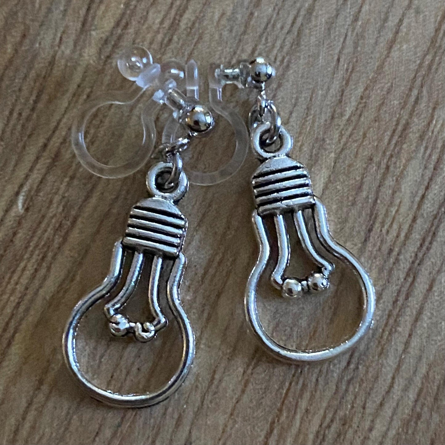 Dangling invisible clip on earrings with silver coloured lightbulb pendants