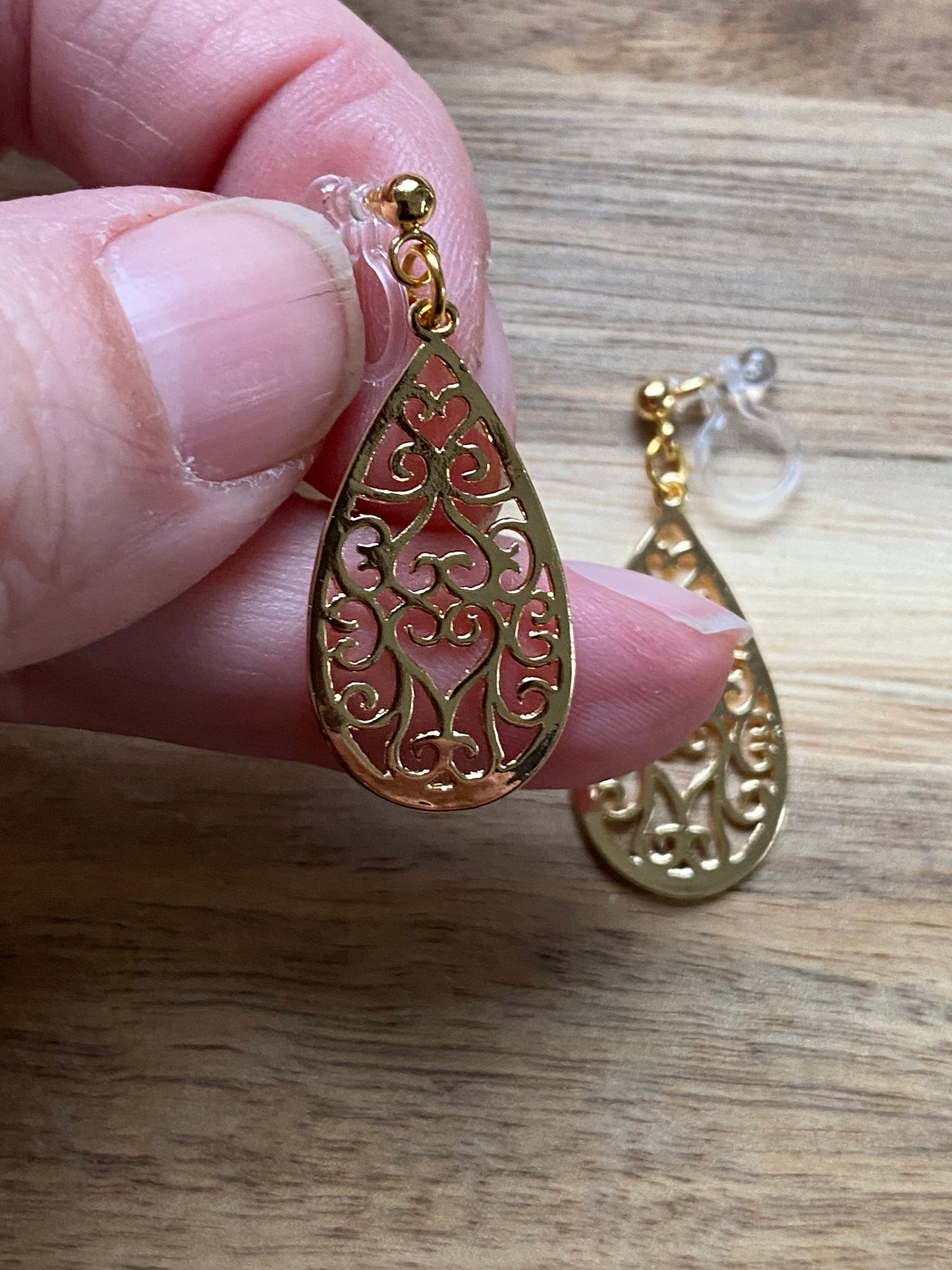 Dangling invisible clip on earrings with gold coloured teardrop pendants