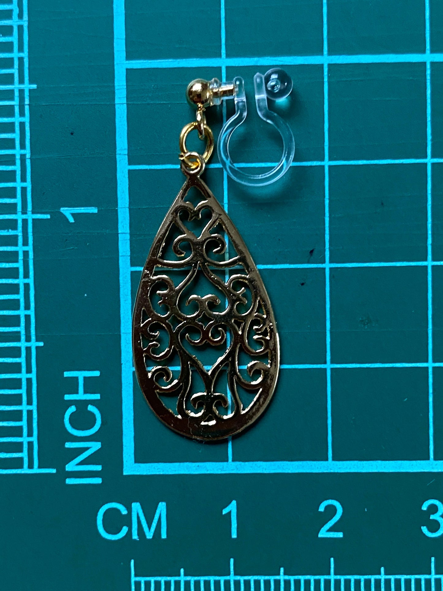 Dangling invisible clip on earrings with gold coloured teardrop pendants